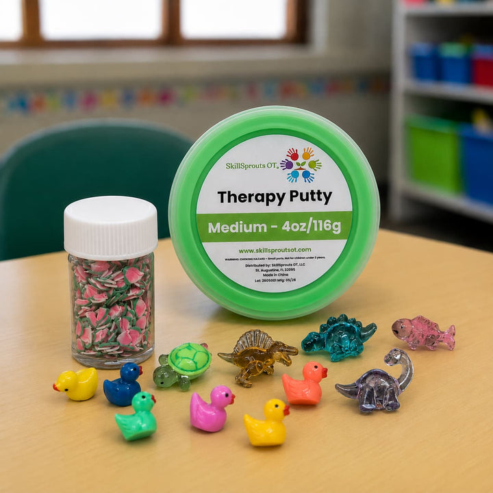 A round tub of SkillSprouts OT Therapy Putty in the shade Medium, alongside a small jar of colorful glitter, with several small dinosaur and duck figurines arranged on a light wood table in a classroom setting.